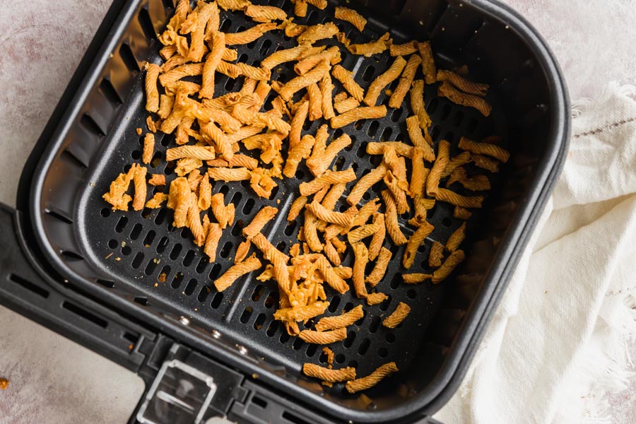 an air fryer basket with cooked pasta inside