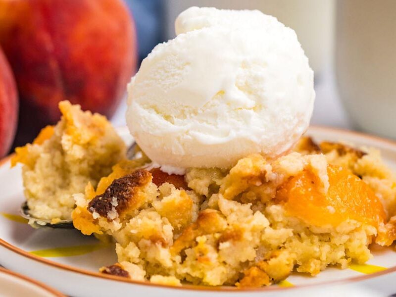 Close up of ice cream on top of a serving of peach cobbler.