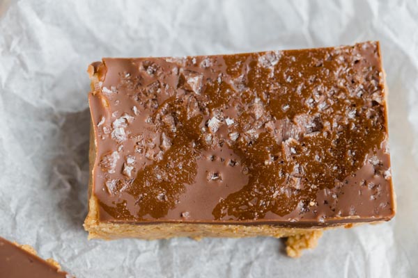 a peanut butter bar with a chocolate layer and flaky sea salt on top