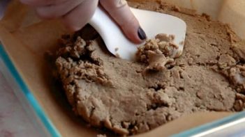 pressing down peanut butter mixture with a white rubber spatula