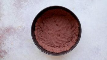 Chocolate cheesecake crust pressed evenly into the bottom of a springform pan.