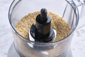 A food processor with ground, crushed peanuts inside.