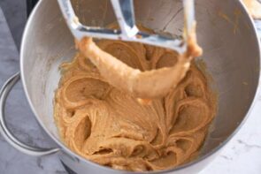 Creamy peanut butter mixture in a bowl over a stand mixer.