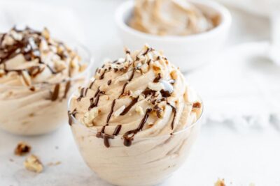 a close up of a swirled peanut butter mousse in a bowl with melted chocolate on top