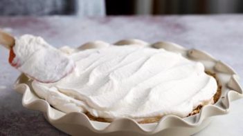 creamy whipped cream being spread on a pie