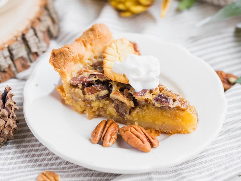 a slice of pecan pie on a plate with pinecones for thanksgiving