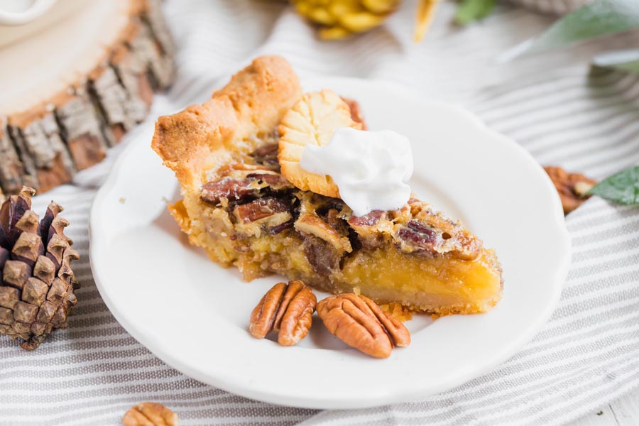 a slice of pecan pie on a plate with pinecones for thanksgiving