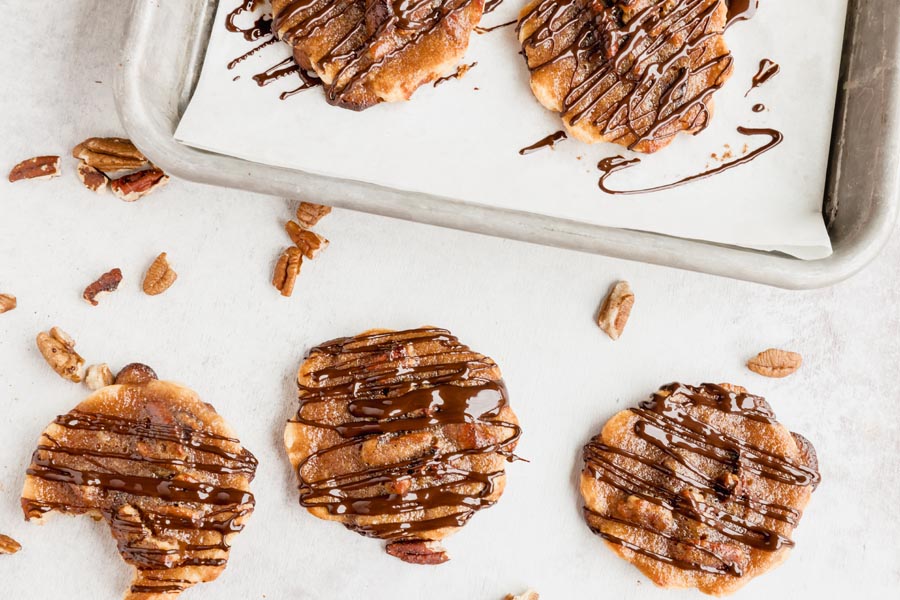 three cookies in a row with a bite out of one and pecans scattered all over