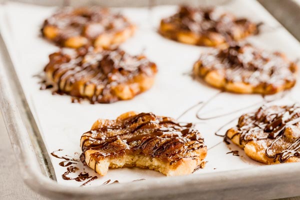 a bite out of a pecan cookie on a tray with other cookies