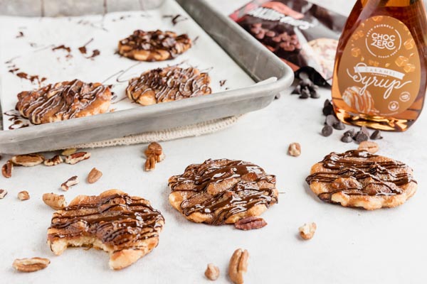 a bite out of a cookie next to other cookies and a bottle of caramel syrup