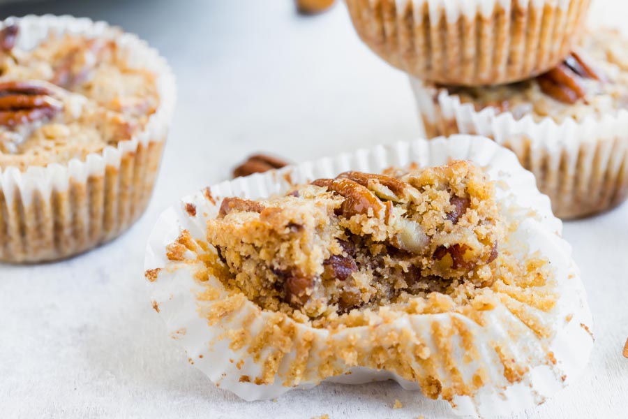 a bite out of a muffin showing the gooey pecan pie center