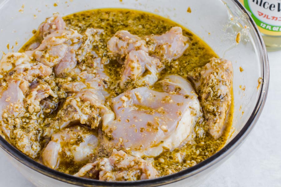 pesto chicken marinading in a bowl