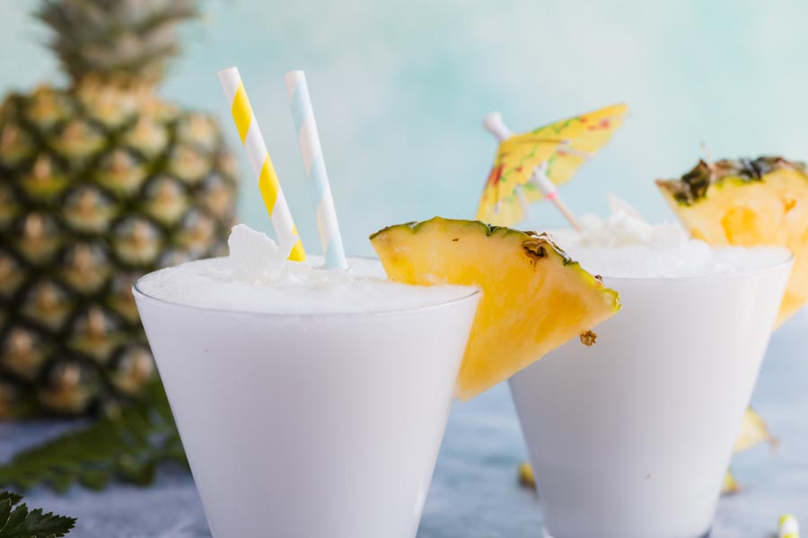 blended pina colada topped with coconut shreds in a cocktail glass