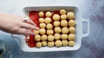 placing dough balls in a row in a white dish