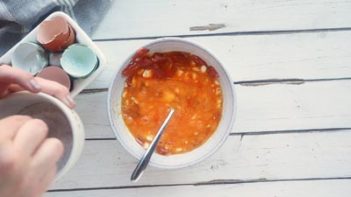 a small bowl with egg mixture next to cracked egg shells