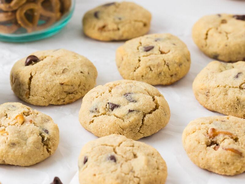 A batch of freshly baked keto pretzel chocolate chip cookies cooling on parchment paper.