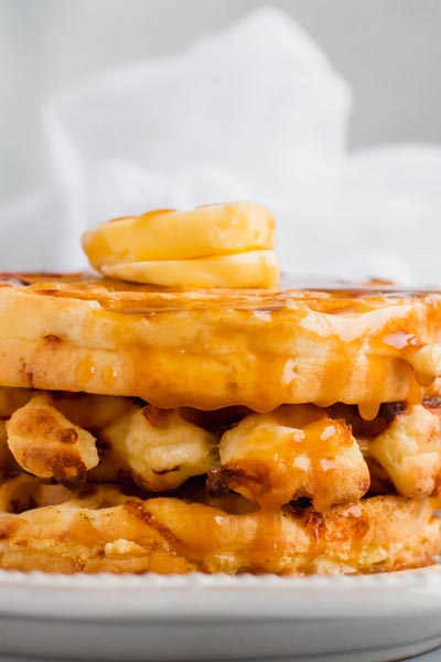 close up of syrup dripping off a stack of waffles