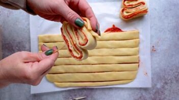 Dough filled pizza folded into an accordion and inserting a skewer into the shape.