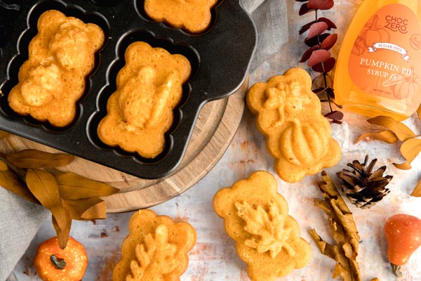 a bunch of mini loaves of pumpkin bread in the pan and outside of it with leaves and pine cones