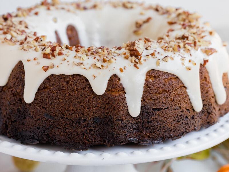 white icing dripping down a bundt cake and topped with nuts