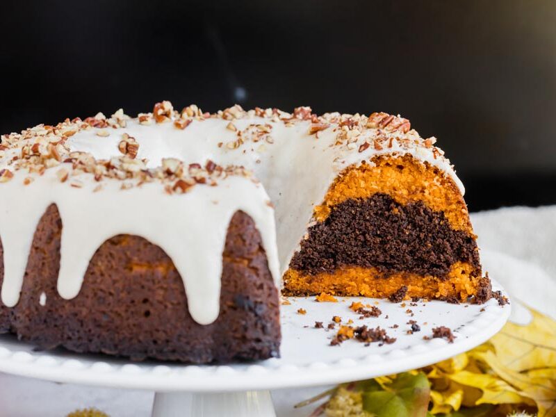 a bundt cake cut showing the layers of orange pumpkin and chocolate