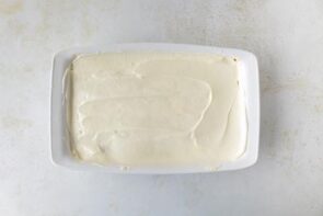 A 9x13 dish with a smooth layer of cream cheese mixture spread across the bottom as the first layer of the dessert.