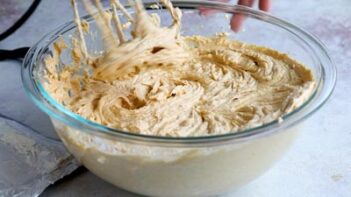 Pumpkin cheesecake filling being whipped with an electric mixer in a glass bowl.