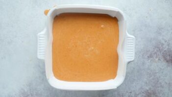 Pumpkin pie filling inside a square baking dish.