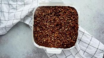 A baked cake topped with pecans on a checkered towel.