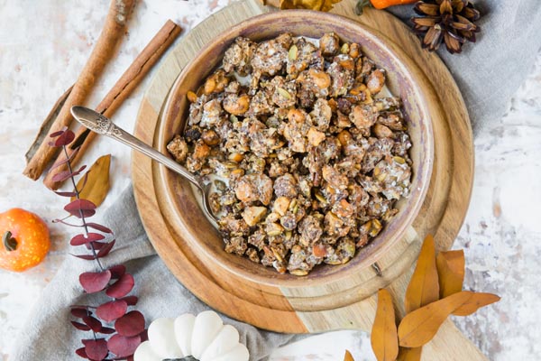 a big bowl of pumpkin flavored granola cereal with a spoon and milk