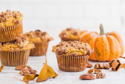 a bunch of pumpkin pecan muffins next to scattered pecans