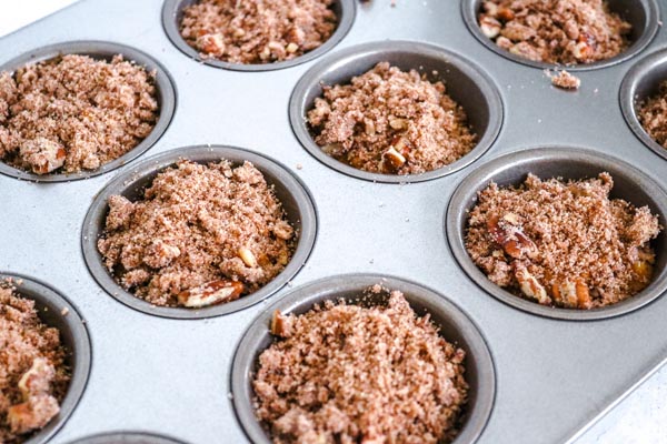 a bowl of pecan streusel topping next to the muffins