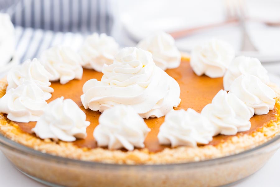 keto pumpkin pie with dollops of whipped cream on top