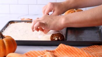 Annie's hands (from Ketofocus) rolling a pumpkin cake by pulling the parchment paper as a guide.