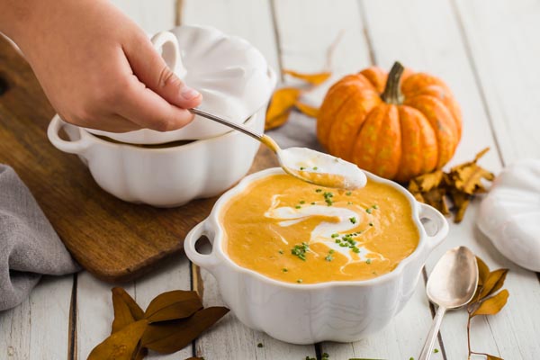 a kid taking a spoonful of creamy pumpkin soup