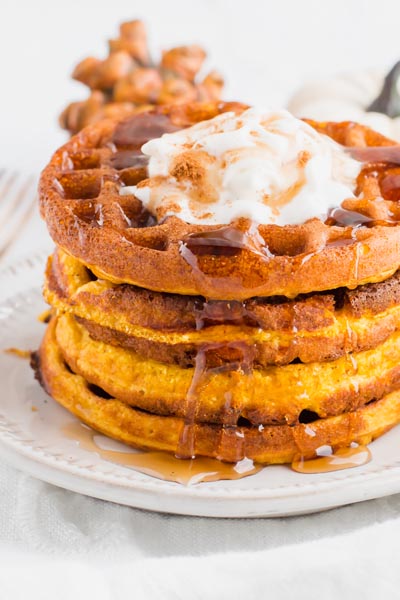 a stack of waffles topped with whipped cream and syrup