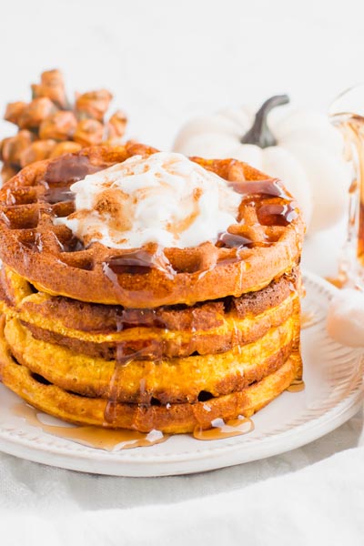 pumpkin waffles covered with syrup in front of a pumpkin