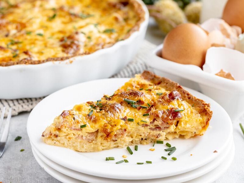 a slice of quiche on a plate topped with chives