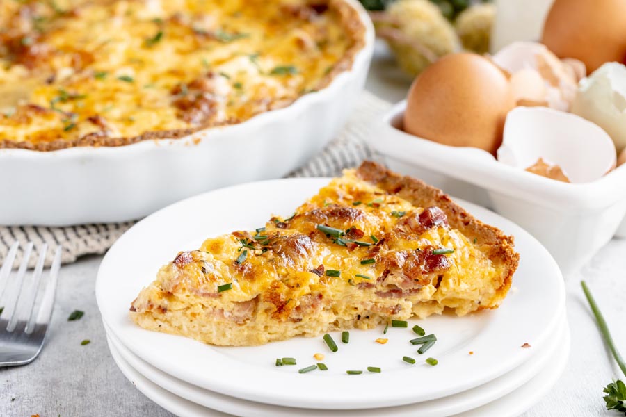 a slice of quiche on a plate topped with chives