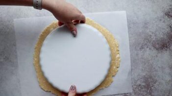 a white tart dish flipped upside down on top of rolled pastry dough