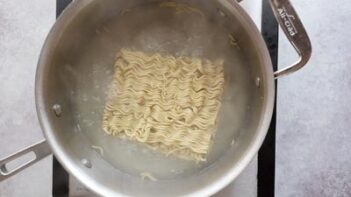 a brick of ramen noodles boiling in a saucepan