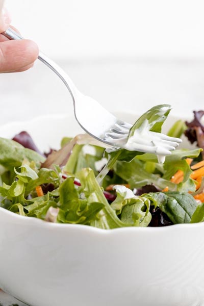 a fork holding a piece of spinach and coated with ranch dressing