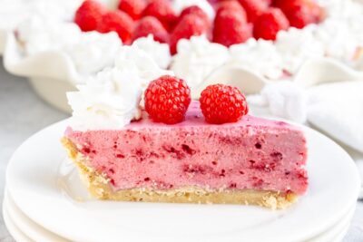 Keto raspberry marshmallow cream pie topped with whipped cream and fresh raspberries.