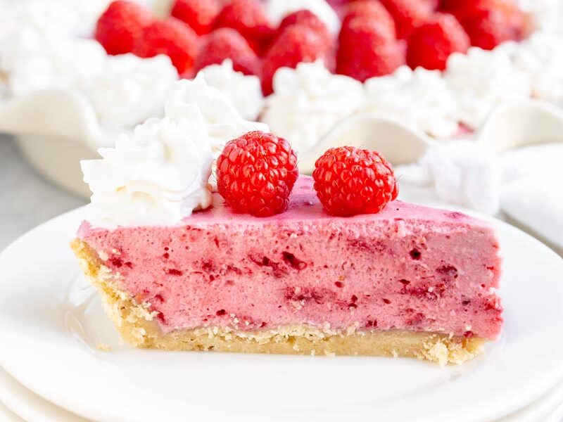 Keto raspberry marshmallow cream pie topped with whipped cream and fresh raspberries.
