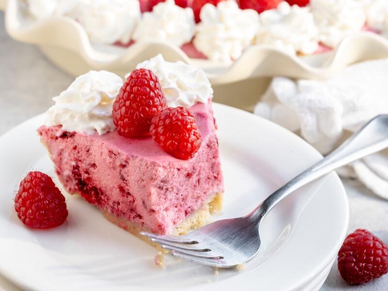Slice of raspberry marshmallow cream pie with whipped cream and fresh raspberries.