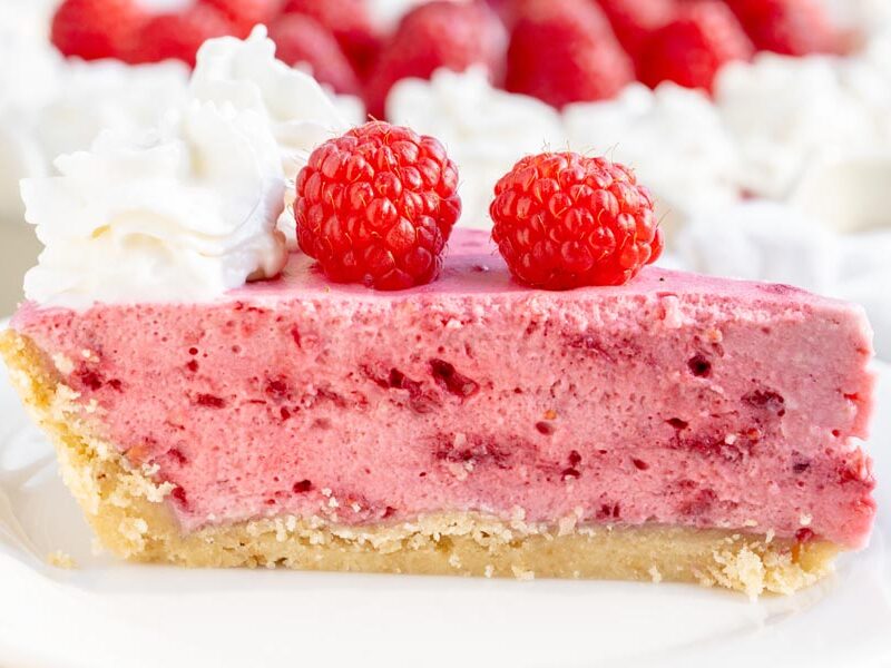 A close-up of keto raspberry marshmallow cream pie showcasing the fluffy raspberry filling and buttery almond flour crust.