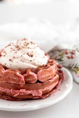 fluffy dessert keto chaffles topped with whipped cream and shredded chocolate next to pink flowers