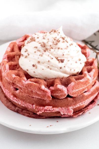 red velvet chaffles on a white plate next to flowers