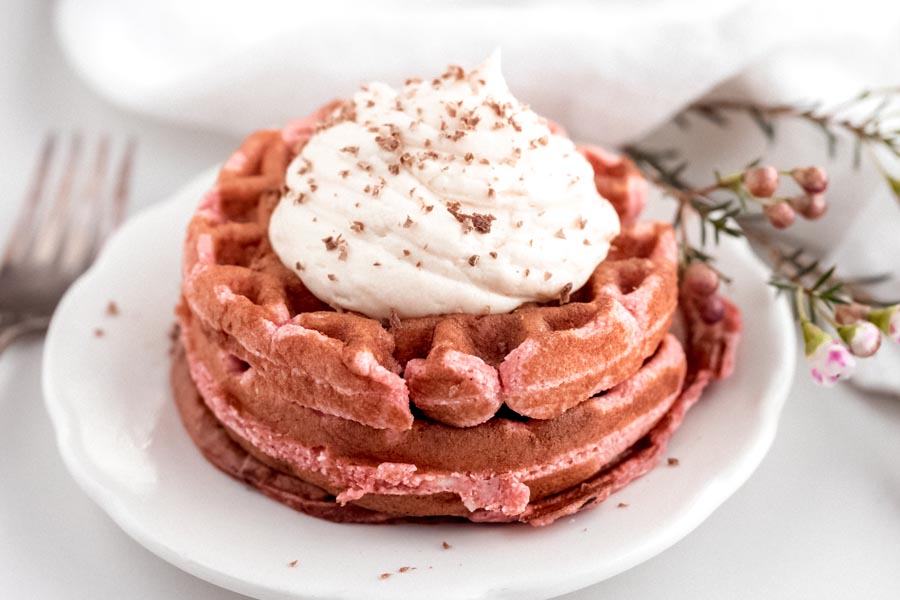 neat stack of keto red velvet waffles with a dollup of frosting