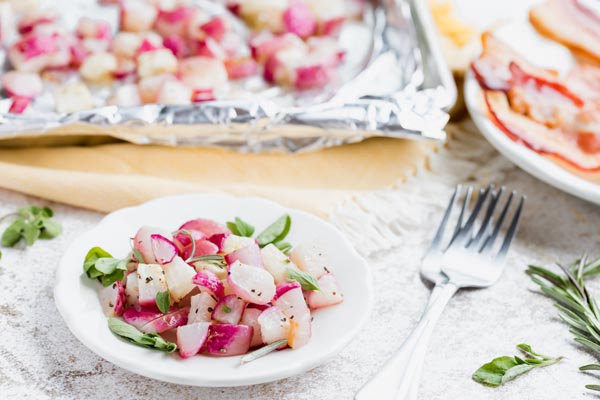 a plate of red radishes that look like potatoes on a plate with a tray behind it